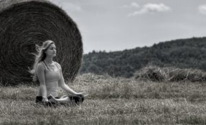 black and white photo of a girl sitting and meditating in a field